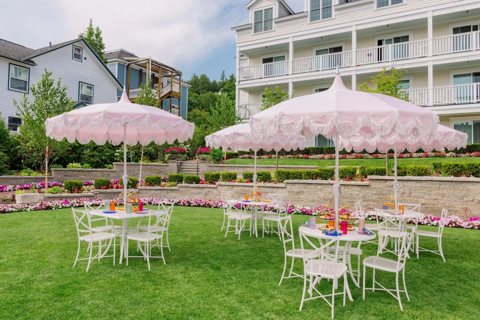Garden tables under pink umbrellas on the hotel lawn