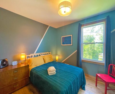 A blue-walled room with a bed and a window