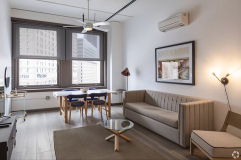 A suite living room with a sofa, a dining table and large windows facing downtown