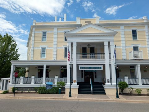 The Hotel Perry's columned entrance and cream-colored facade by day