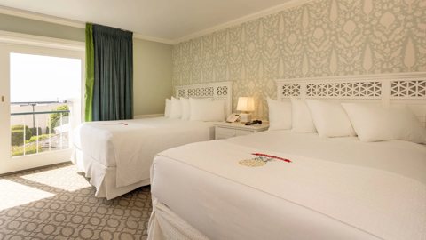 A guest room with two queen beds and patterned wallpaper at the Hotel Perry