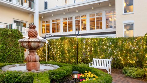 A garden courtyard with a fountain and string lights beside the hotel