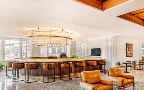 A round bar with a glass chandelier and leather armchairs in the hotel lobby
