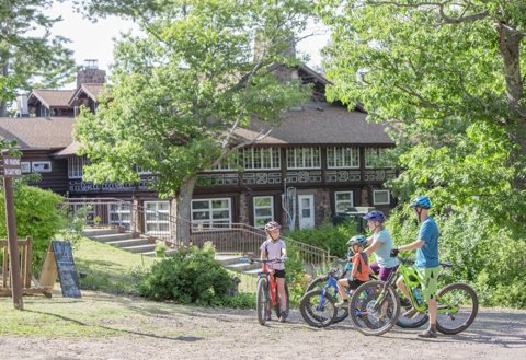 Cyclists in front of the log main lodge in summer