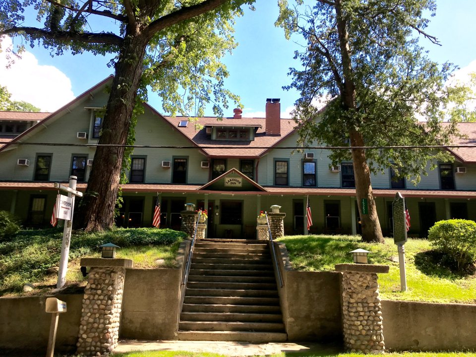 The Lakeside Inn's green clapboard building, wide porch and stone-pillared steps