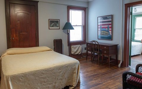 A guest room with an old wooden door, a desk and a sunroom with wicker chairs