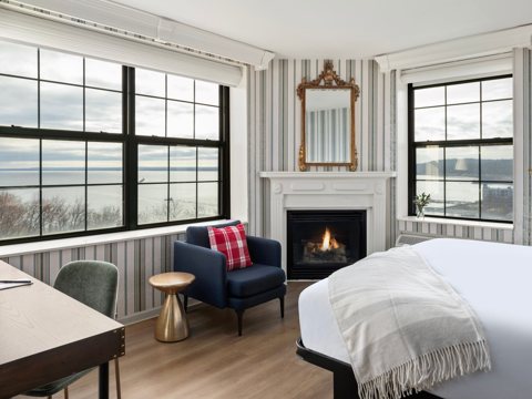 A guest room with a fireplace and large windows overlooking Lake Superior