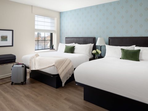 A guest room with two queen beds and a blue papered wall