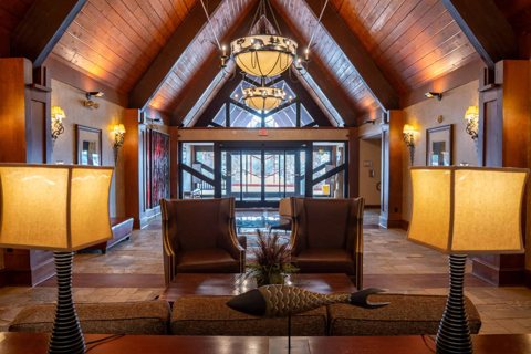 The hotel's wood-paneled lobby under a high peaked ceiling, with a chandelier, leather armchairs and table lamps