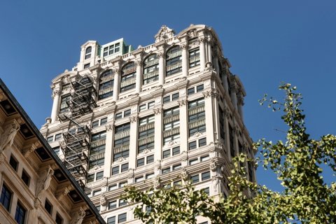 The ornate pale stone upper floors of the Book Tower against a blue sky