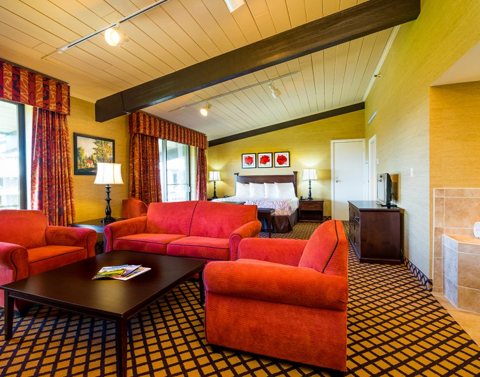 A spacious suite with red sofas, a coffee table and a king bed