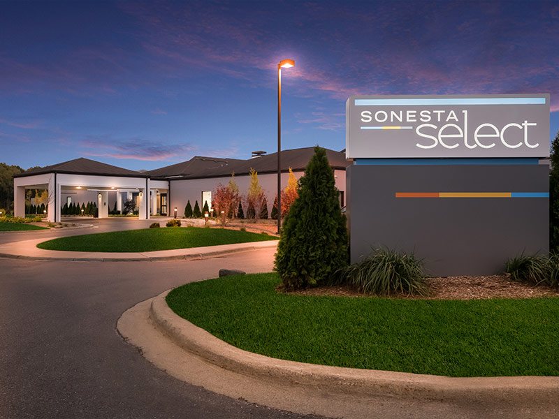The hotel entrance with the Sonesta Select sign at dusk