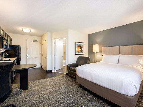 A suite with a queen bed, an armchair, a table and a kitchenette