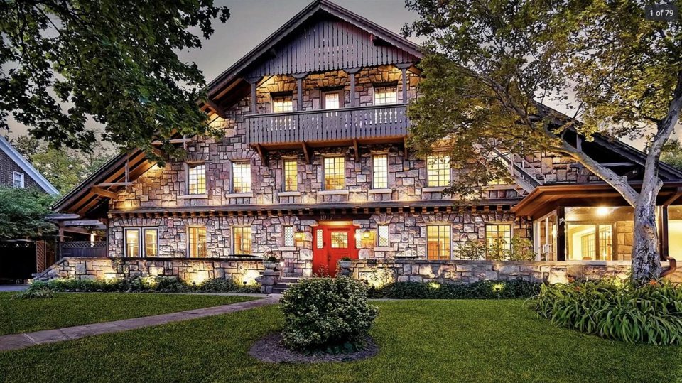 The Stone Chalet's stone and timber main house lit at dusk, with a lawn in front