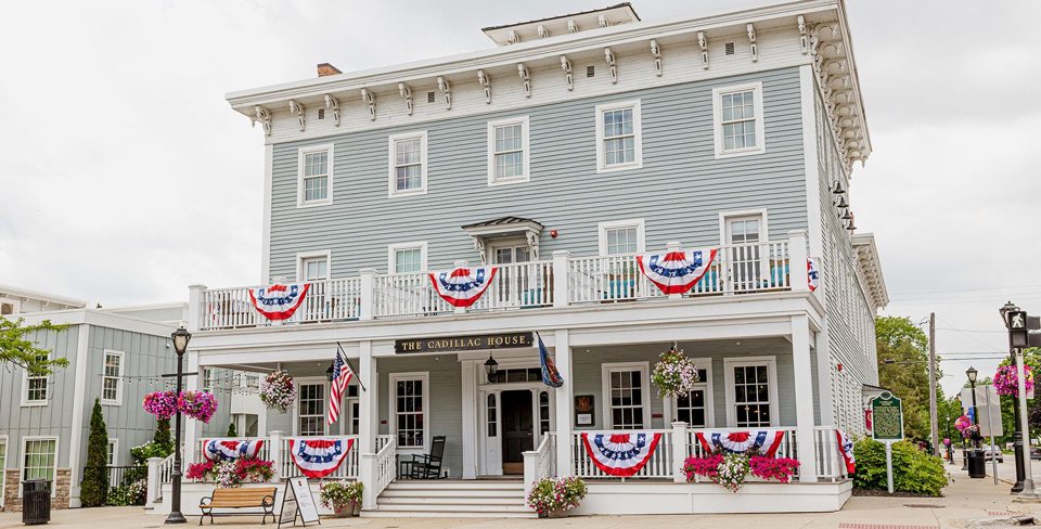 The Cadillac House's three-storey pale blue wooden building with flag-draped porches