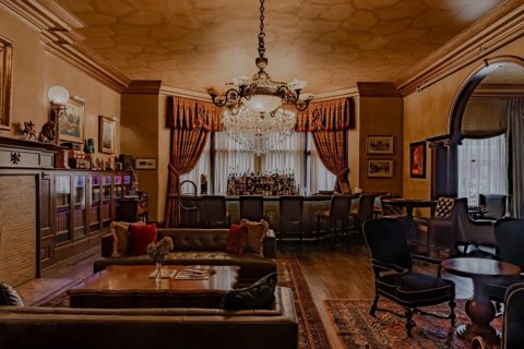 A wood-panelled lounge with a crystal chandelier, sofas and a bar