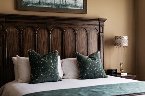 A guest room with a carved wooden headboard and green cushions