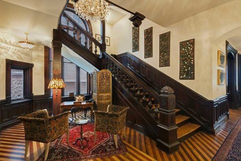 The entrance hall with a carved wooden grand staircase, a chandelier and armchairs