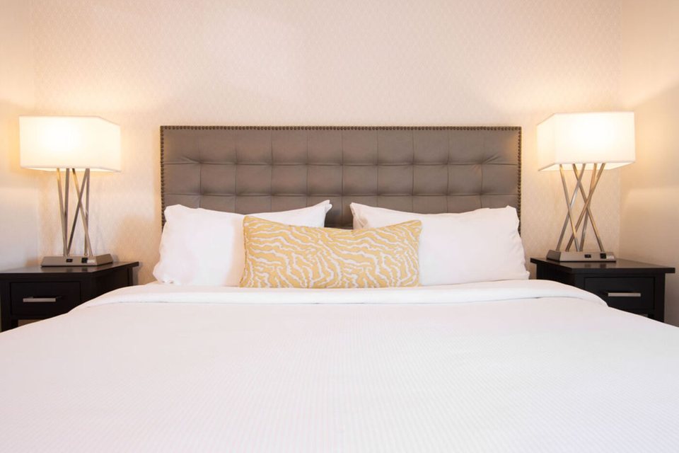 Guest room with a king bed, an upholstered headboard and two bedside lamps