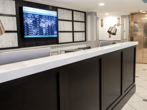 The front desk with a white counter and a wall-mounted screen