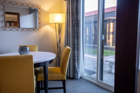 Guest room seating area with a round table, two yellow chairs and a glass door to a patio