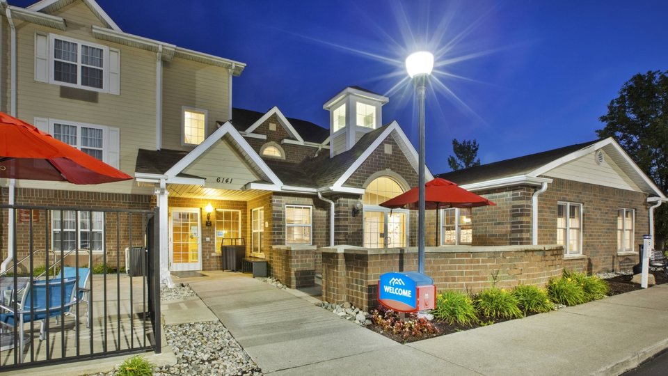The hotel's gabled entrance lit up in the evening, next to the fenced pool terrace