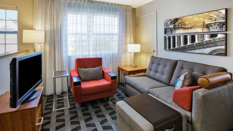 Suite living area with a gray sofa, a red armchair and a TV