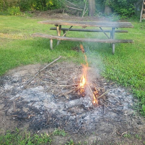 Campfire and picnic table on the grass