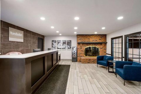 The front desk with a dark counter, a brick fireplace and blue armchairs