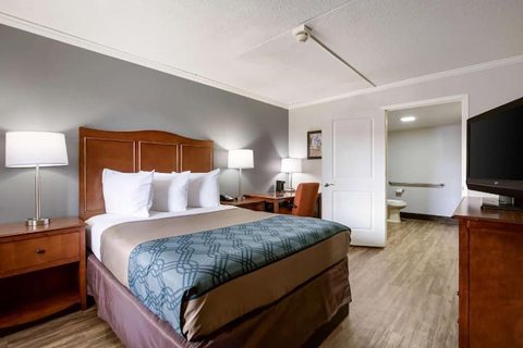 Guest room with a queen bed, wooden furniture and a TV