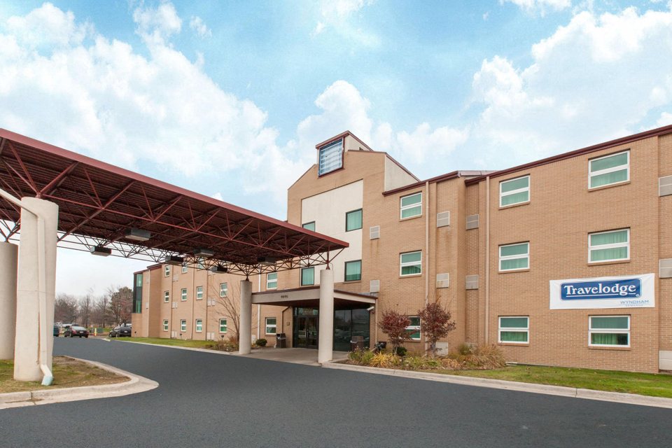 The hotel's three-storey building with the Travelodge sign and the covered drive-through entrance