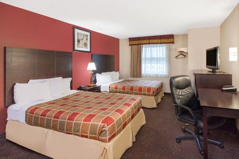 Guest room with two beds in plaid covers, a desk and a burgundy wall