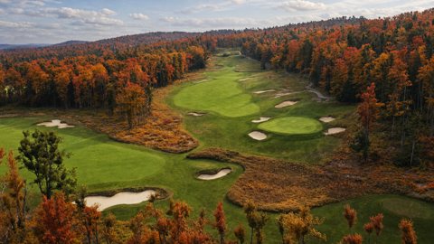 One of the resort's golf courses among autumn woods, seen from above