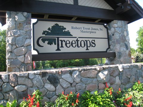 The stone-walled Treetops entrance sign with flowers