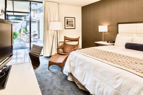 Guest room with a king bed, a lounge chair and a glass door leading outside