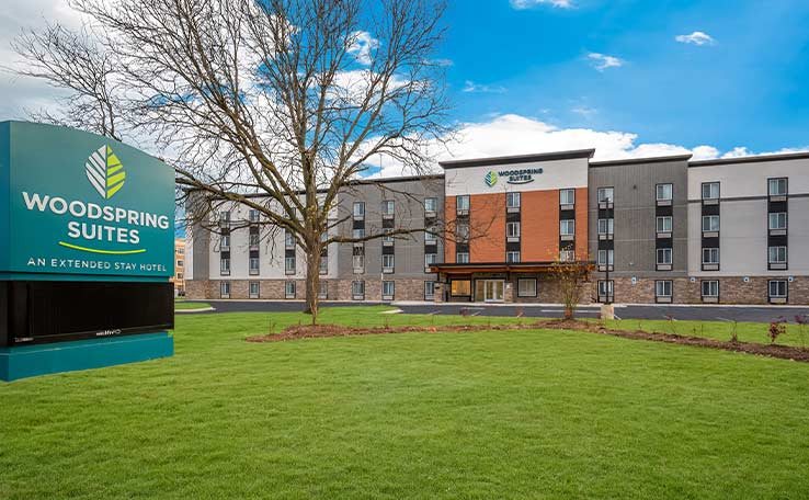 The hotel's four-storey building with the WoodSpring Suites sign and front lawn