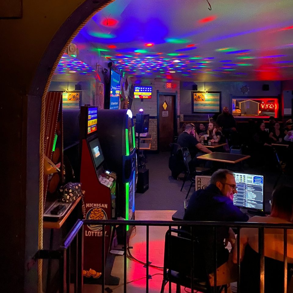 The bar room with colorful disco lights, gaming machines and guests at tables