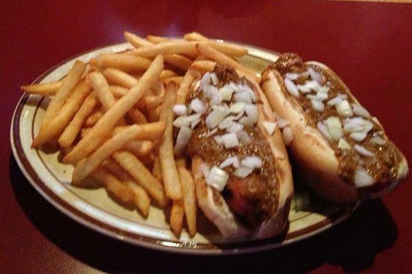 Chili dogs topped with onions and fries on a plate