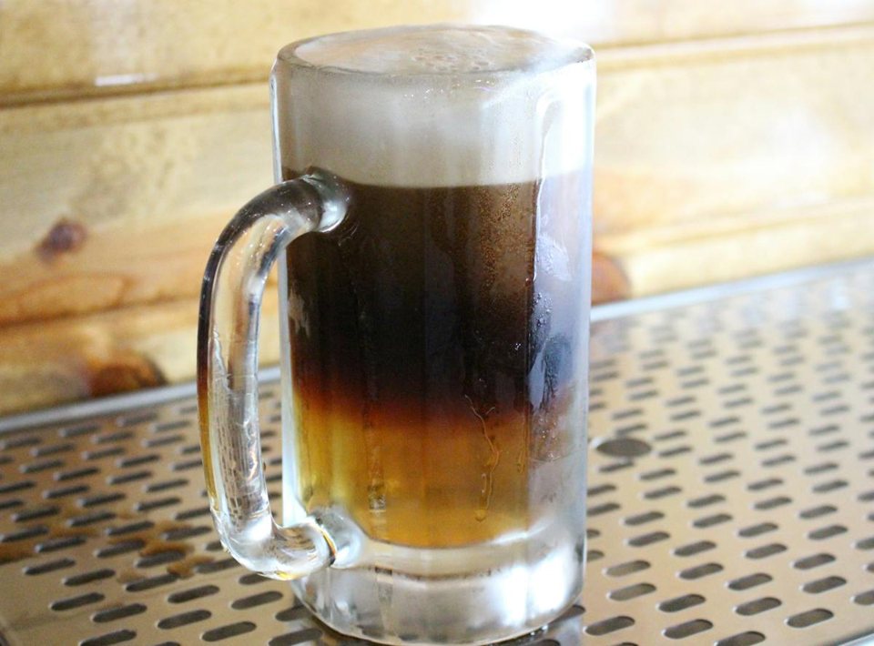 A mug of layered two-tone beer on a metal table
