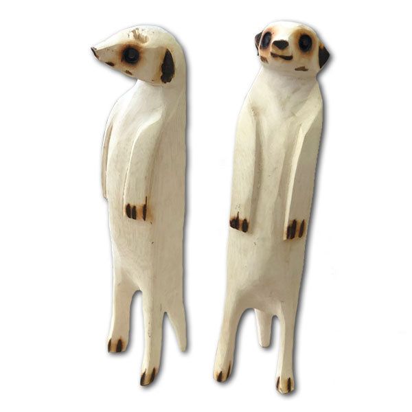 Two carved white meerkat figurines standing side by side