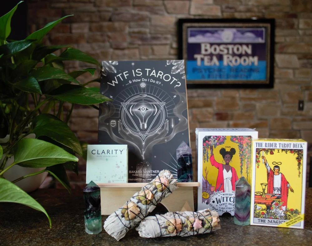 Tarotkártyák, könyv és zsályaköteg a Boston Tea Room cégtáblája előtt