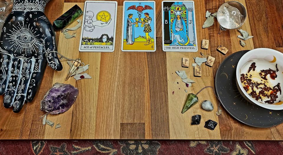 Tarotkártyák, kristályok és gyógynövények egy fa asztalon