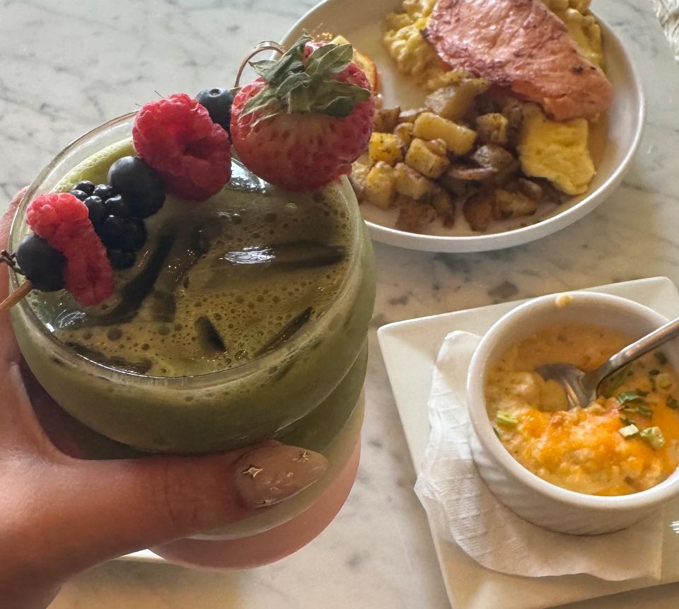 Zöld smoothie bogyós gyümölcsökkel, mögötte reggeli fogások