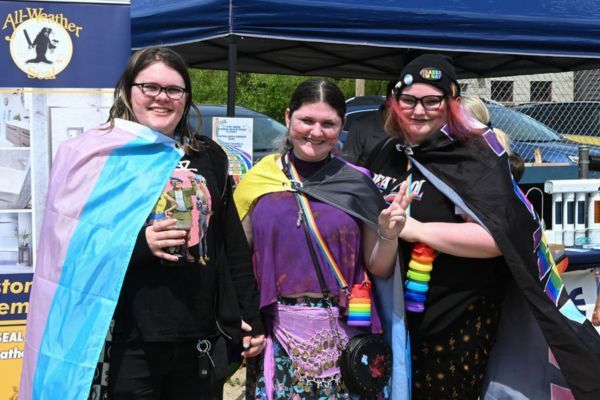 Három barát Pride-zászlókba burkolózva a fesztiválon