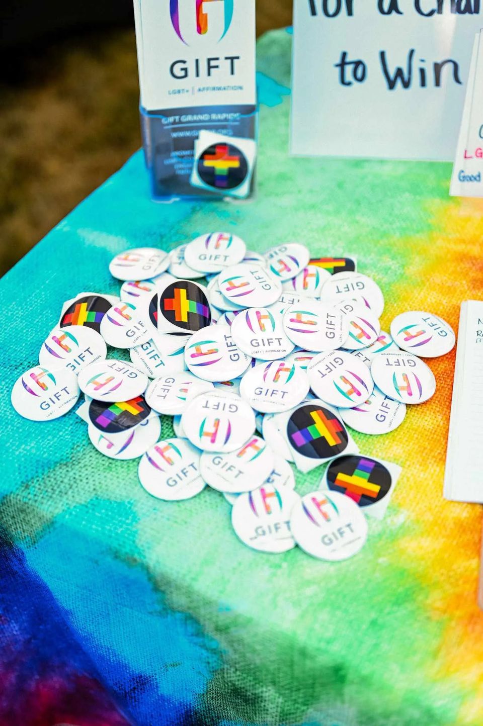 GIFT-kitűzők szivárványos terítőn egy információs asztalon