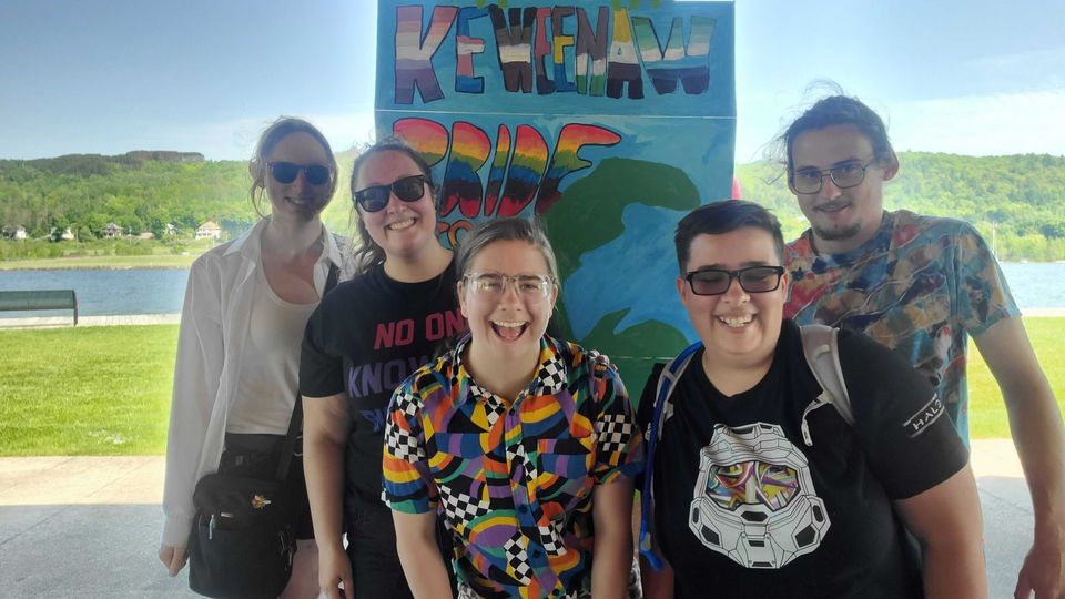 Barátok csoportképe a festett Keweenaw Pride tábla előtt