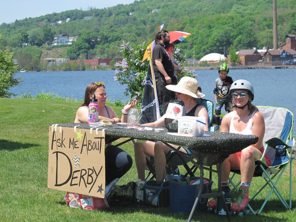 Információs asztal „Ask me about Derby” táblával a tóparton