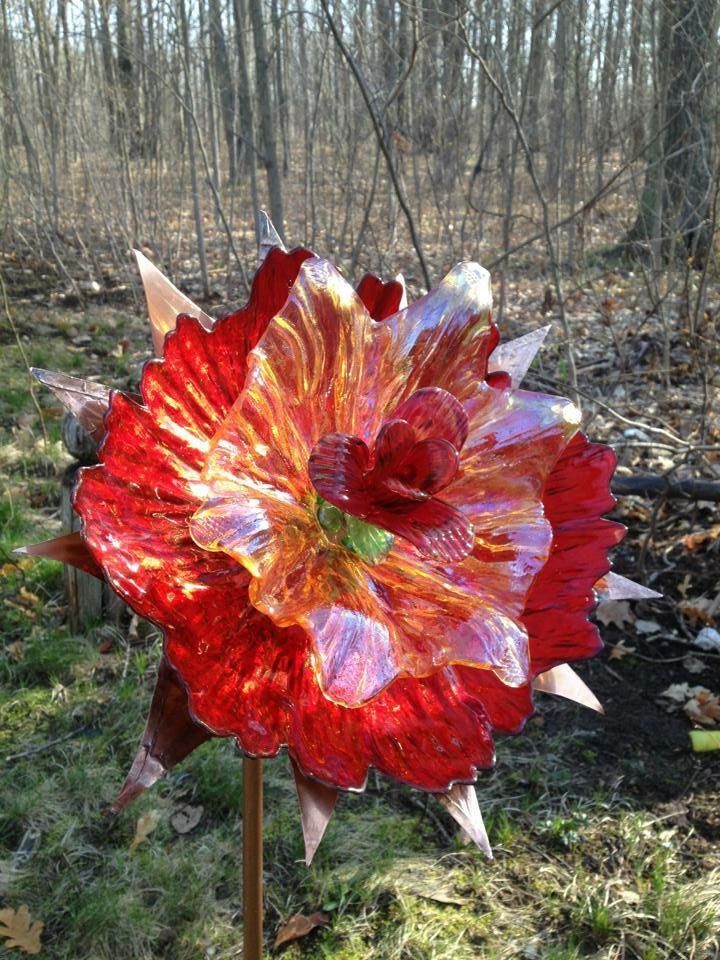 Red glass flower garden stake at the edge of early spring woods