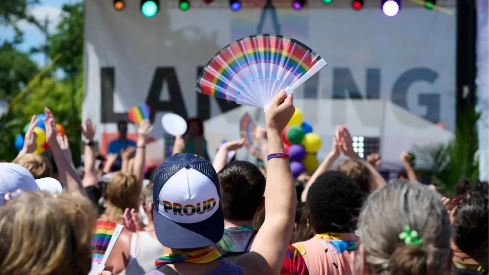 Magasba tartott szivárványos legyező a Lansing Pride színpada előtt