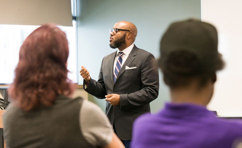 A presenter in a suit leads a training session